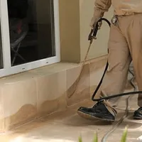 General pest control technician spraying exterior perimeter around a home in Lakeland, FL