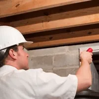 Termite inspection technician checking a basement wall and framing for termite activity in Lakeland, FL